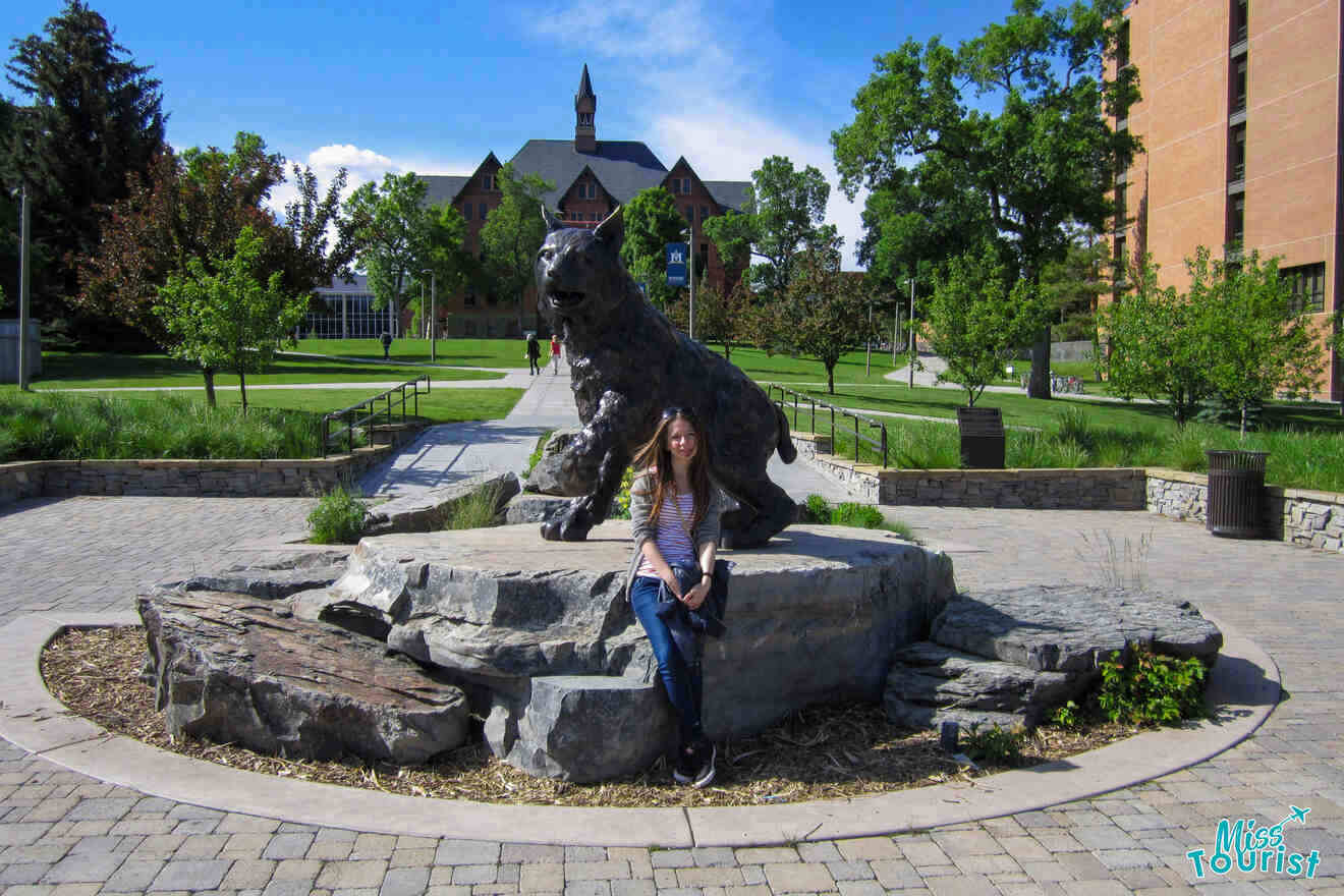 A woman is posing in front of a statue of a wolf.
