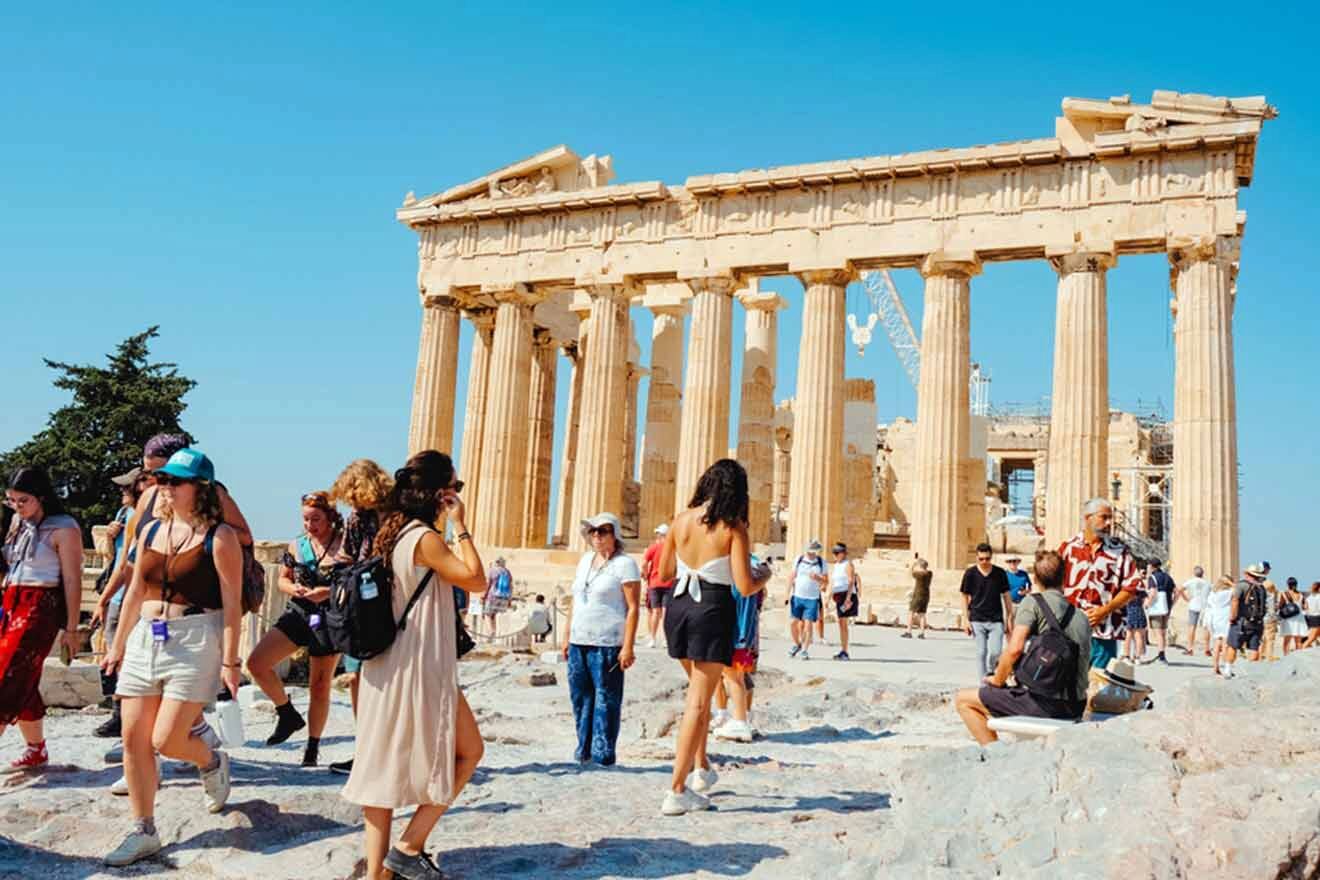 Visitors exploring the ancient Parthenon on the Acropolis of Athens, with clear blue skies above and historic ruins surrounding the iconic temple.