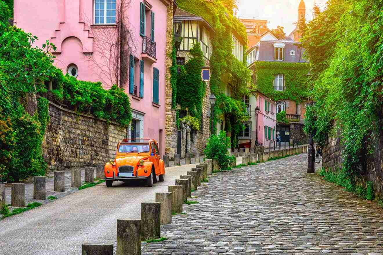 An orange car drives down a cobblestone street in paris.