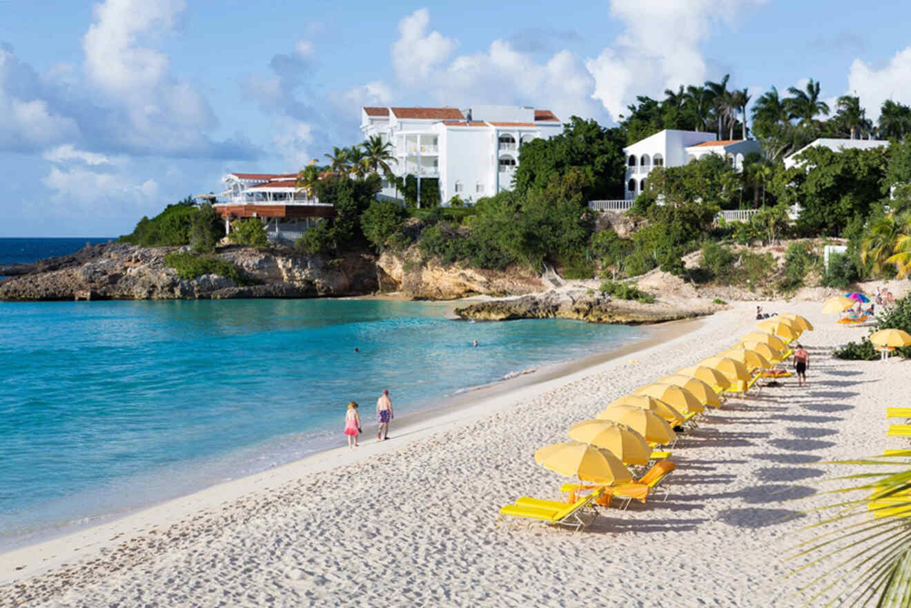 A beach with yellow lounge chairs and a hotel in the background.