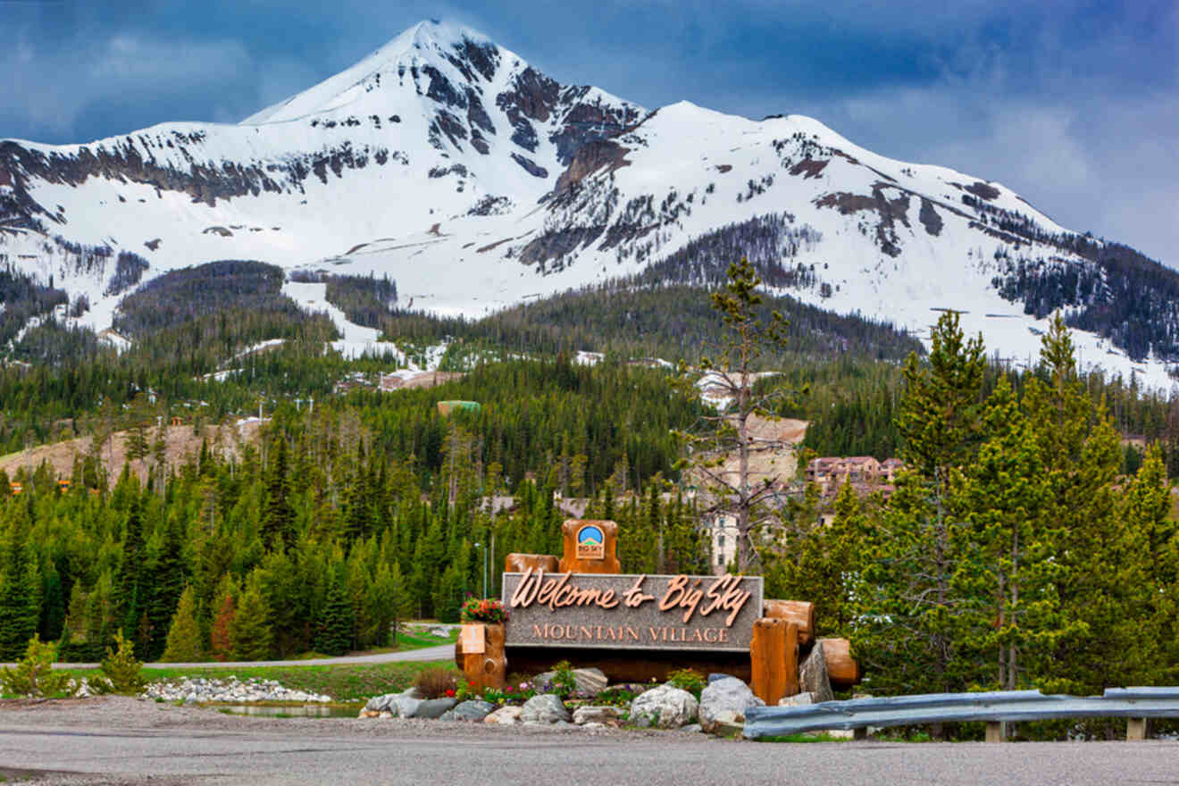 A sign in front of a mountain with snow capped mountains.