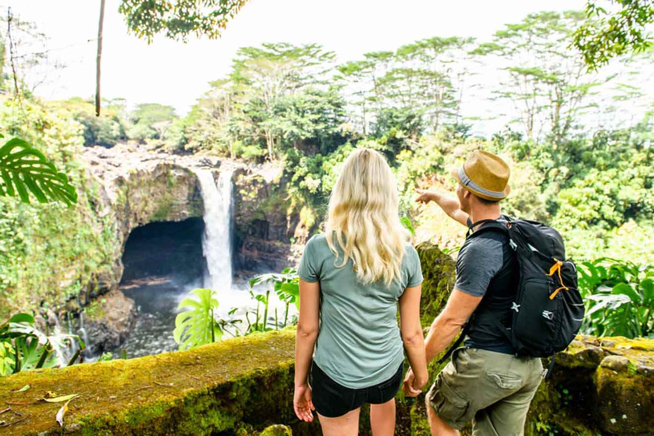 Two people standing in front of a waterfall in hawaii.