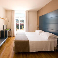A hotel room with wooden floors and a large bed.