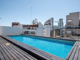 A swimming pool on top of a wooden deck in a city.