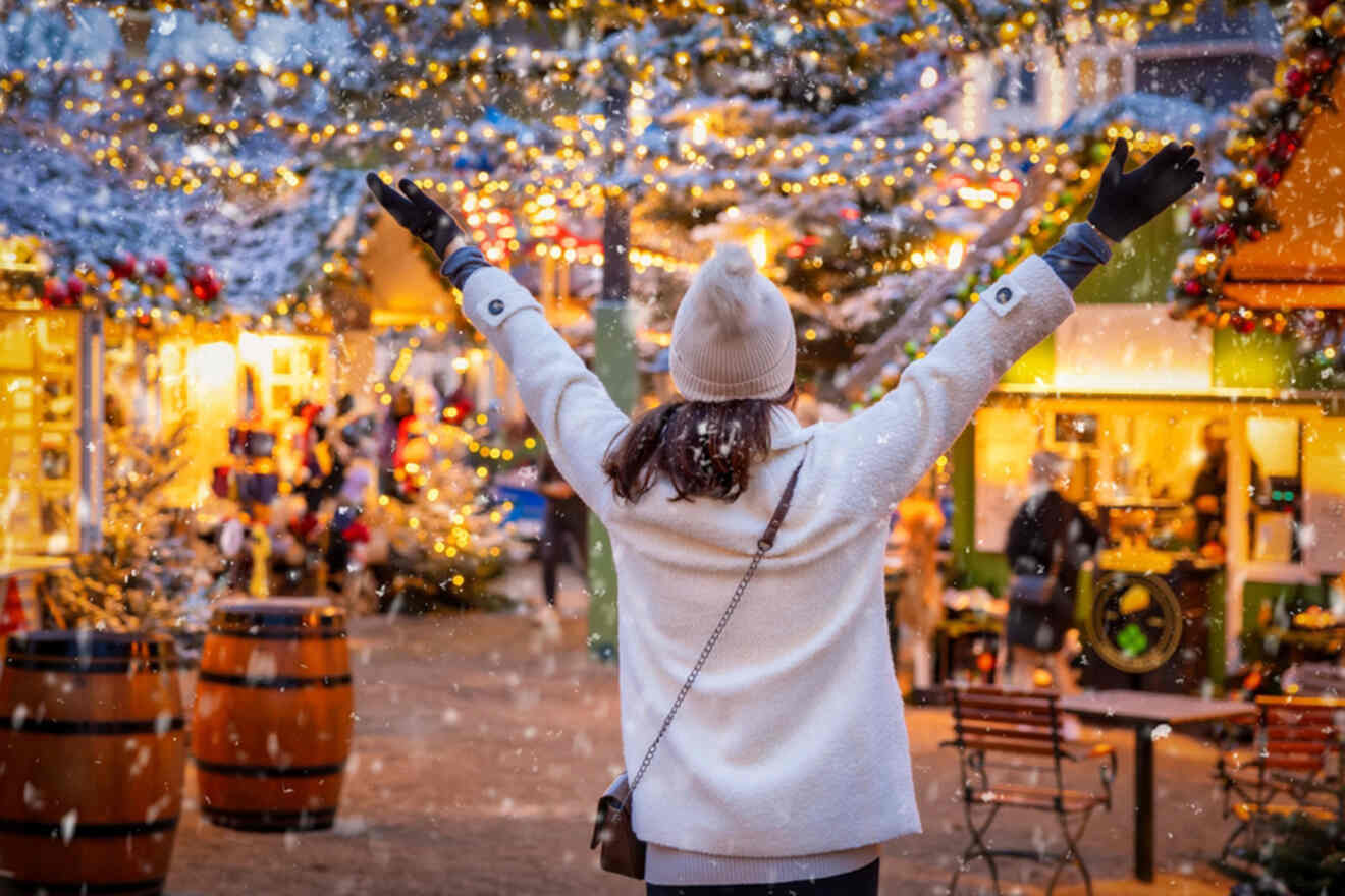 a girl with raised hands in the middle of a Christmas market with twinkling lights sky