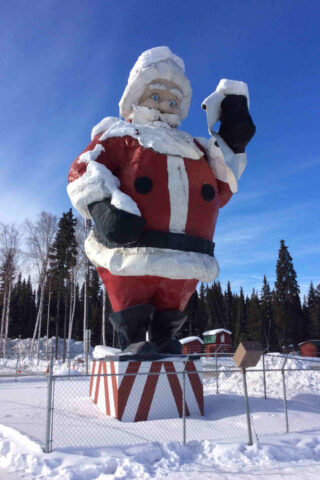 A large santa claus statue in the snow.