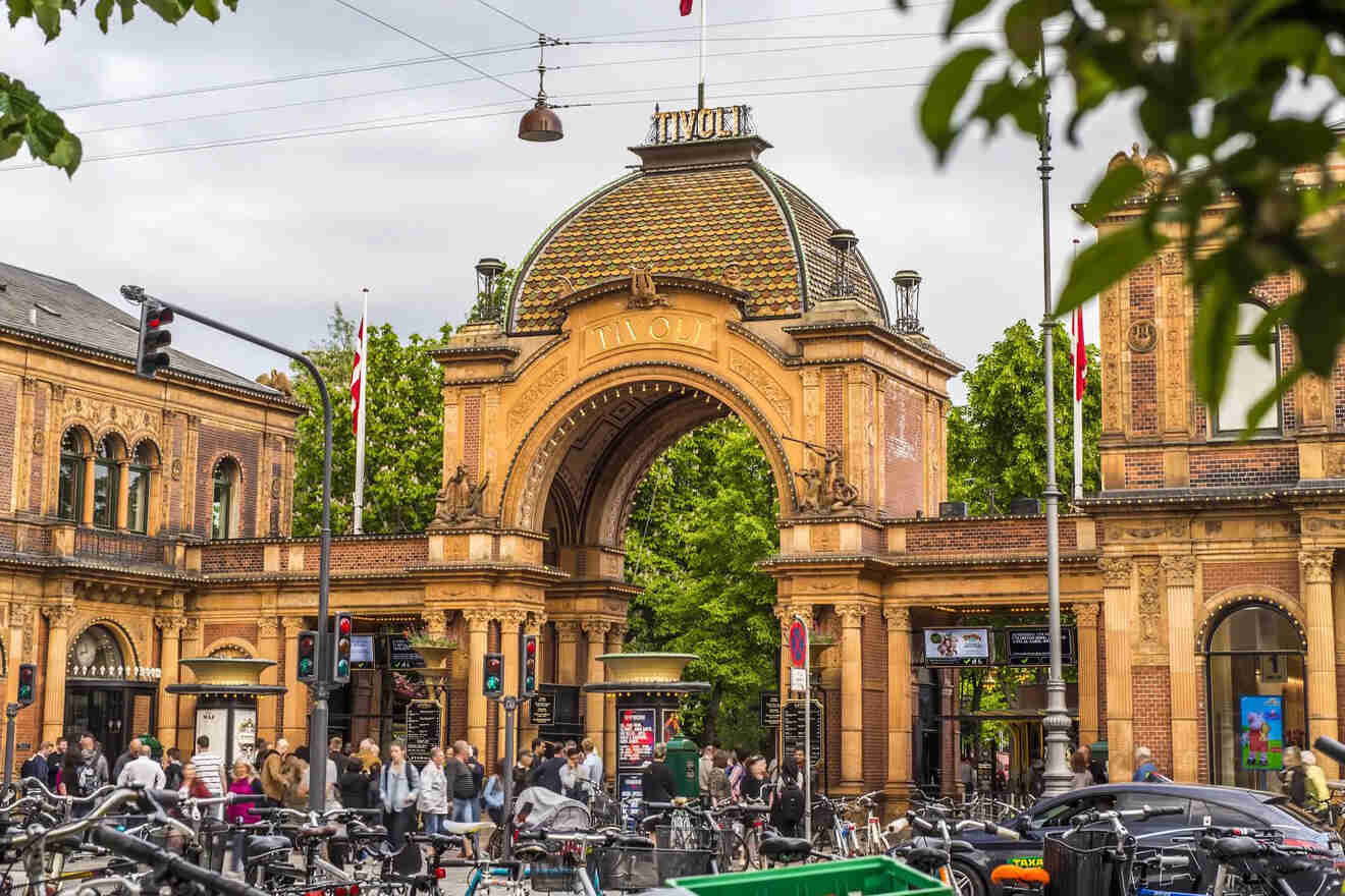 The historic entrance to Tivoli Gardens in Copenhagen, adorned with intricate details and surrounded by vibrant activity on a cloudy day
