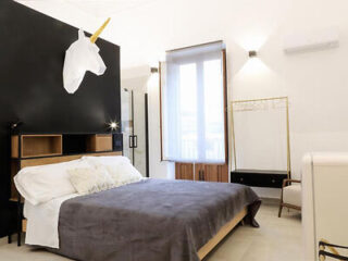 A black and white bedroom with a unicorn head on the wall.
