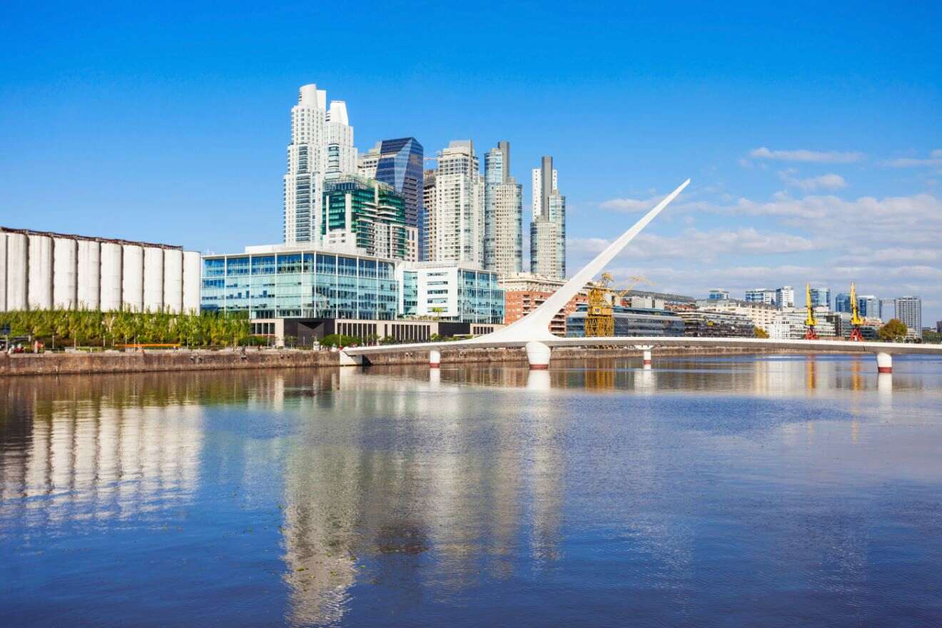 view of a city skyline by the water with an unusual bridge