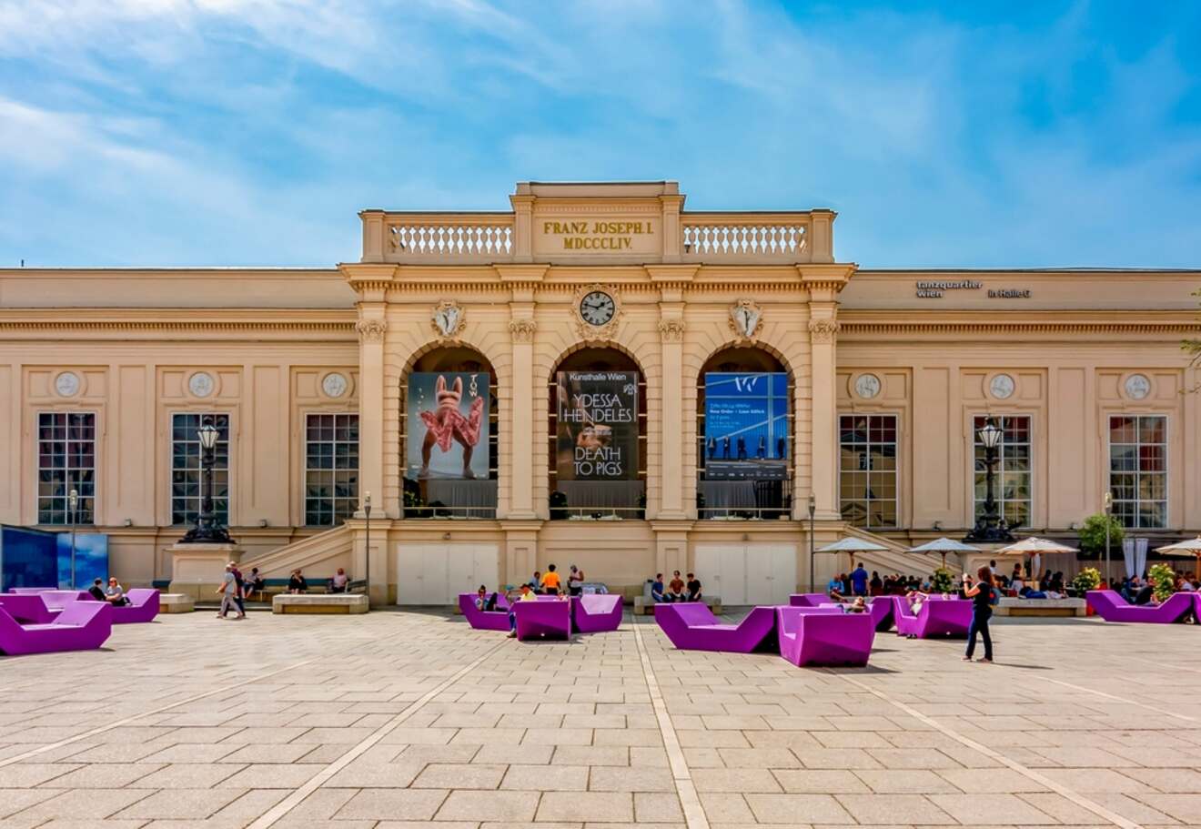 people sitting on benches in front of a museum