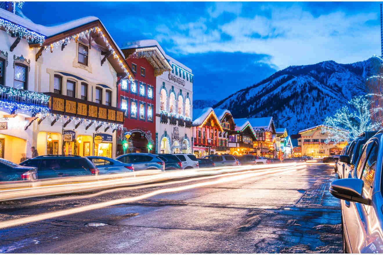 a street with houses decorated with twinkling lights and mountains in the background