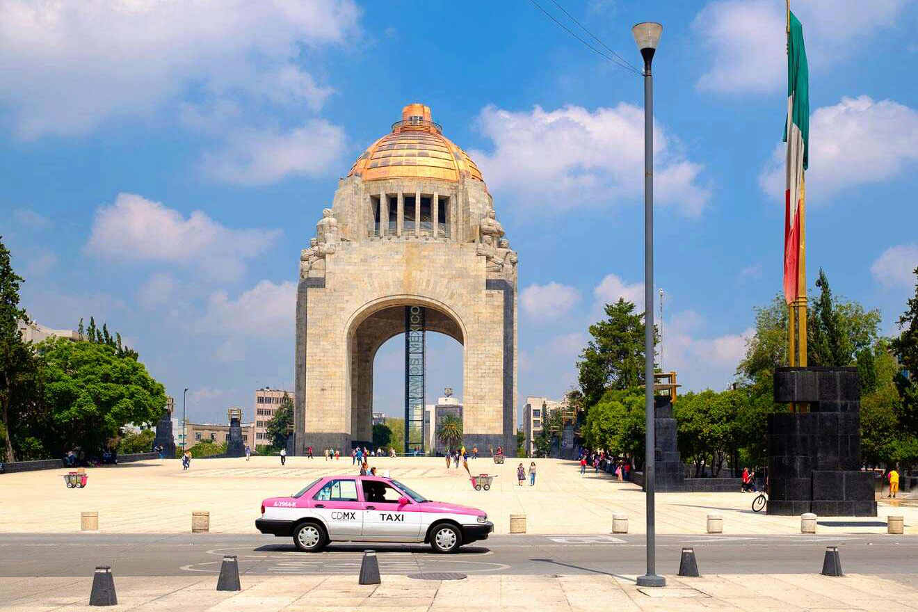 A pink taxi parked in front of a monument in Mexico City