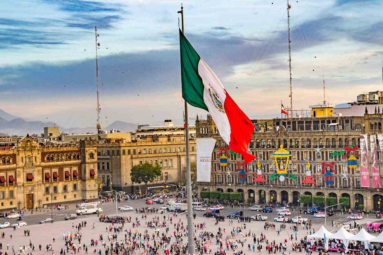 A mexican flag is flying over a main square in mexico city.