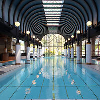 Interior of the Victoria-Jungfrau Grand Hotel's indoor pool with a symmetrical design, arched ceiling, and skylights providing a bright, airy atmosphere