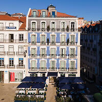 Elegant blue facade of a traditional Lisbon building with outdoor seating at the cafe on the ground floor under the open sky