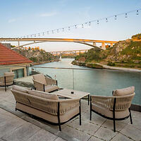 Riverside terrace in Porto, Portugal, with comfortable outdoor seating overlooking the serene Douro River and the iconic bridges at dusk