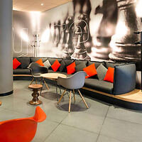 Hotel lobby with chic decor, featuring a large black and white chess-themed mural and vibrant orange cushions