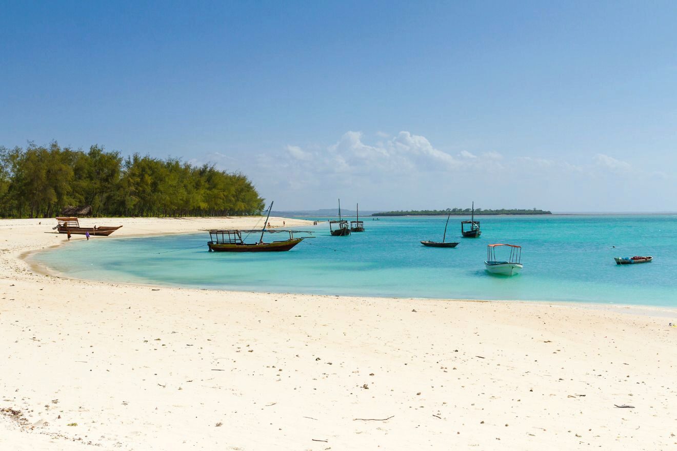 View of the white sandy Kendwa beach in Zanzibar with boats docked in the water.