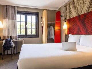 Hotel room with a striking red headboard and surfboard decor, blending modern and sporty themes