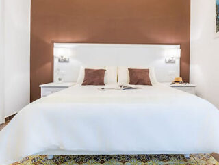 Bedroom with a patterned bedspread, white walls, two bedside tables