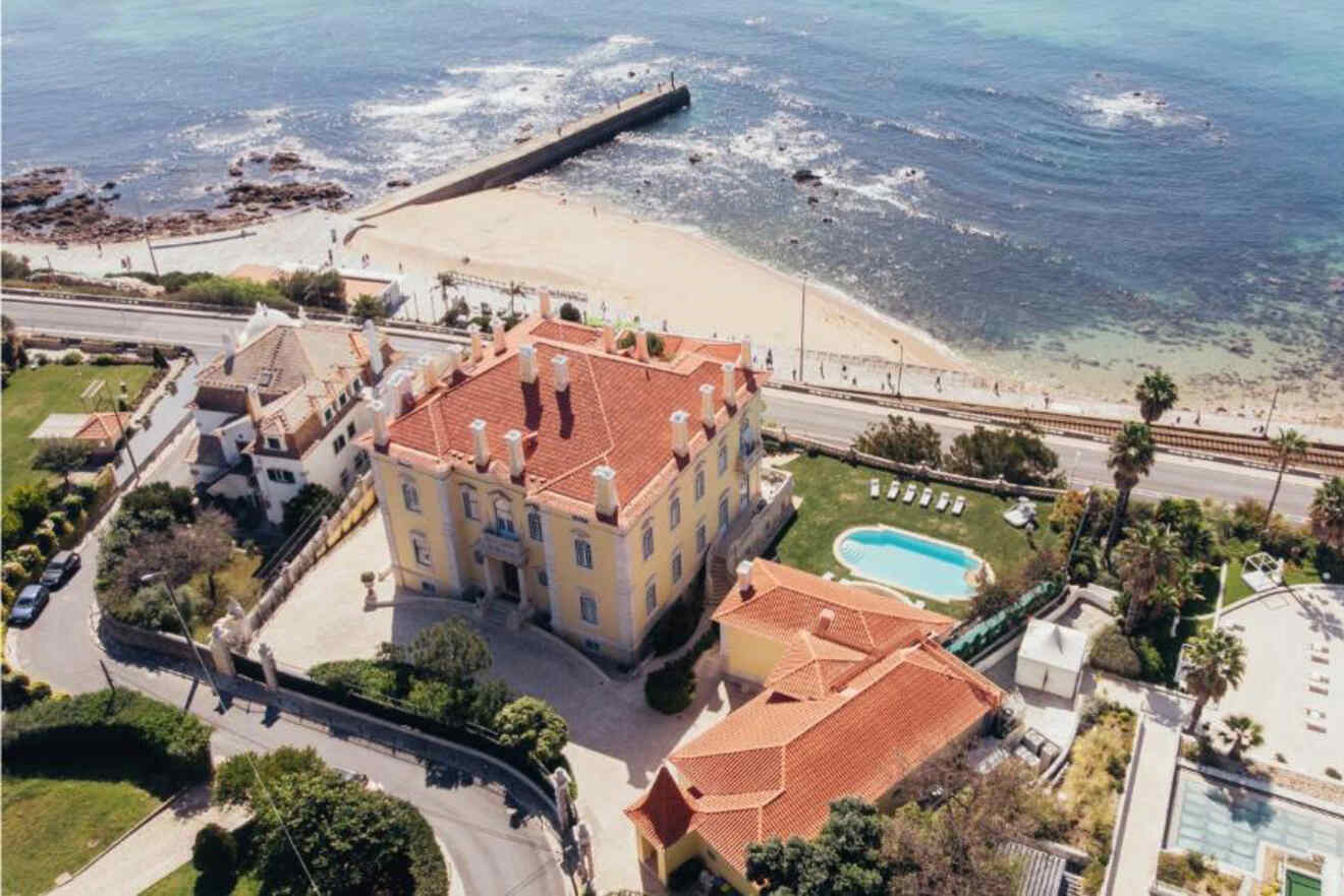 Aerial shot of a luxurious beachfront hotel near Lisbon, showing its proximity to the sandy beach and the azure waters of the Atlantic Ocean