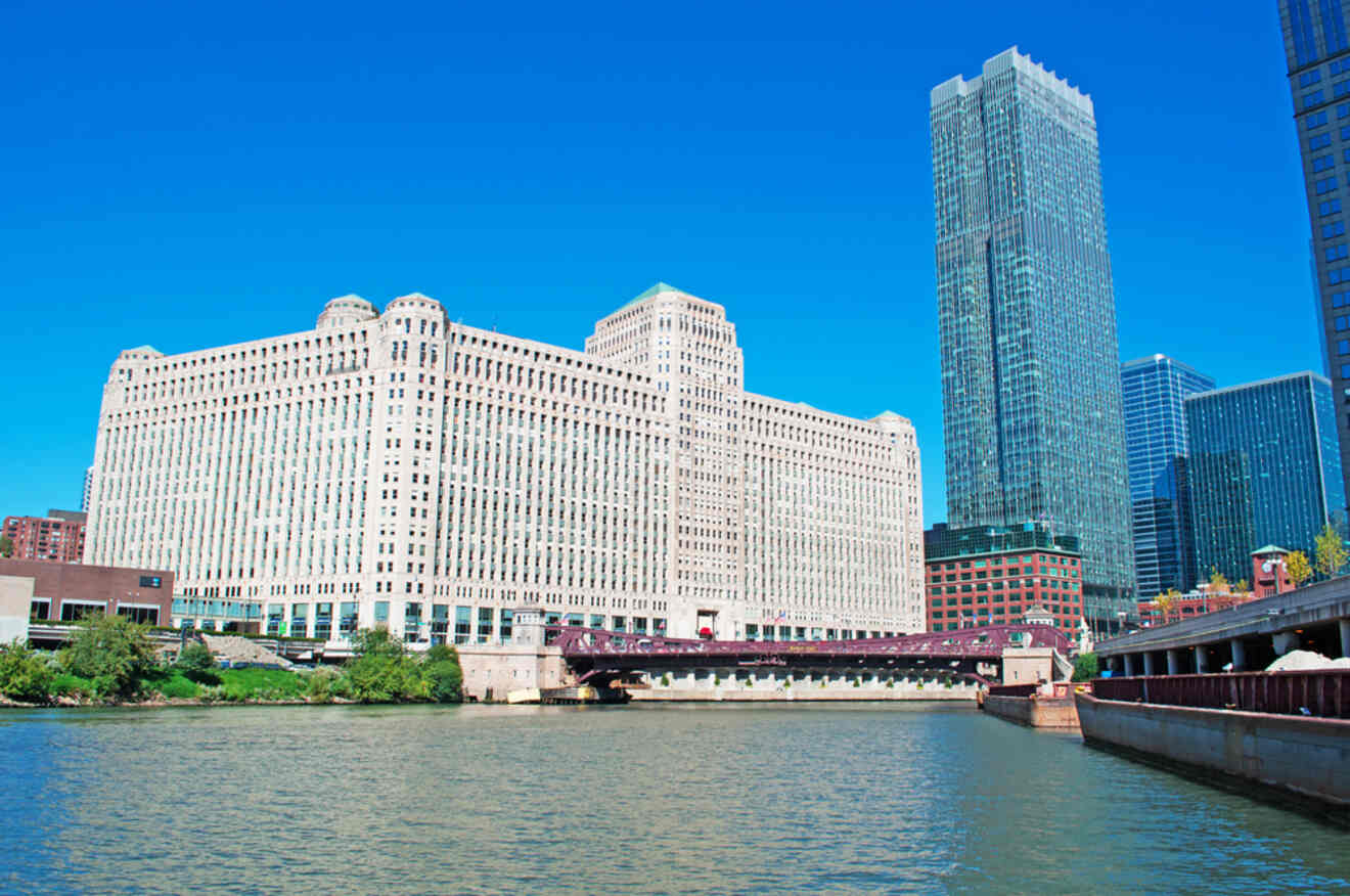 The Merchandise Mart building in Chicago, a massive structure with classic windows, overlooking the Chicago River on a sunny day