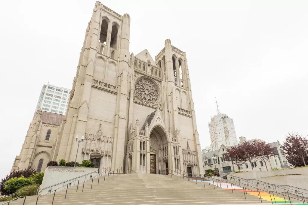 The imposing facade of Grace Cathedral in San Francisco, with its intricate Gothic architecture and large rose window, under an overcast sky.