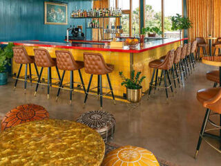 A blue and yellow hotel bar with stools and chairs.