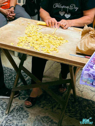  close-up scene of traditional pasta making, where hands are crafting and cutting dough on a wooden board
