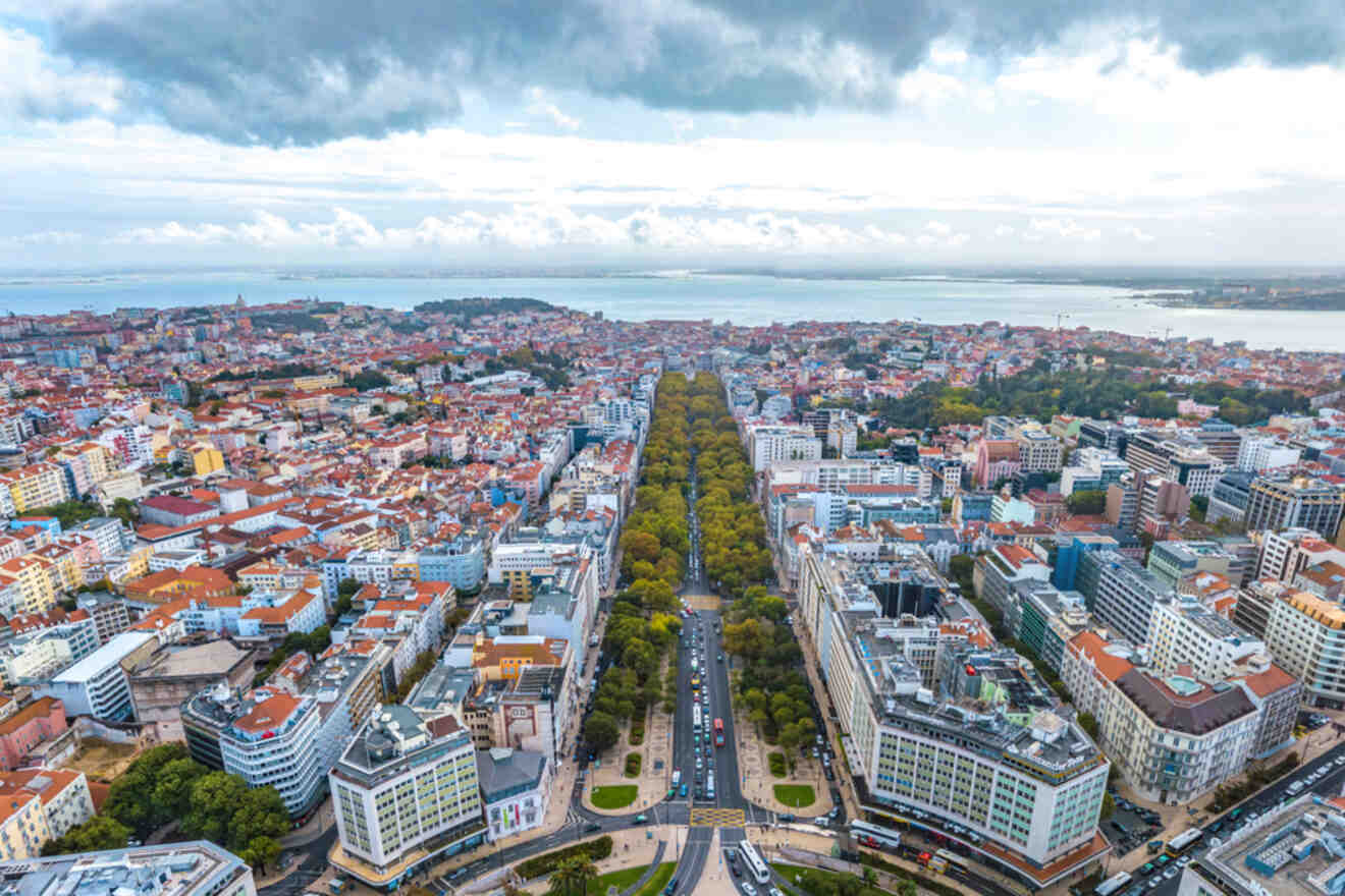 Aerial view of Avenida da Liberdade in Lisbon, showcasing the long, tree-lined boulevard stretching toward the Tagus River, with overcast skies above