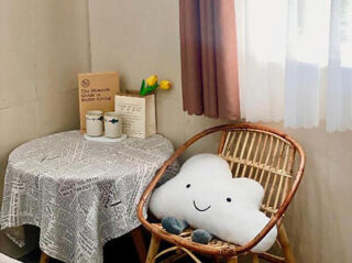 A cloud shaped pillow sits on a table next to a window.