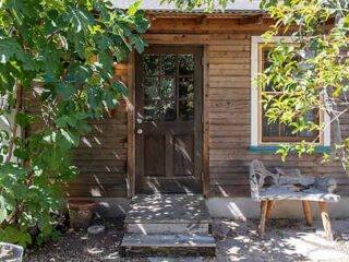 the entrance to a wooden cabin with a wooden chair next to it