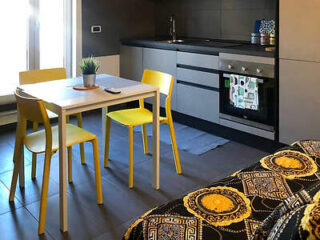 A vibrant and colorful kitchen with a yellow and black mosaic table, matching yellow chairs, and modern appliances