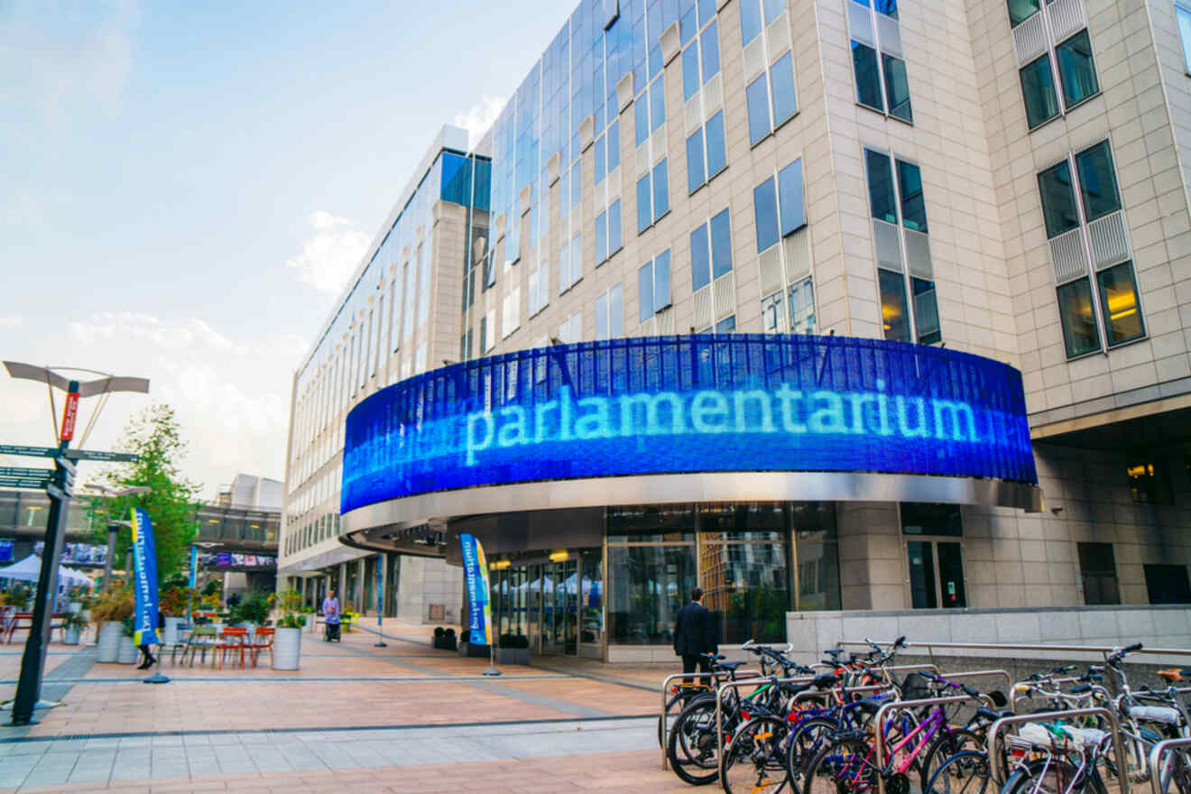 Parlamentarium building in Brussels with a prominent blue banner, bicycles parked outside
