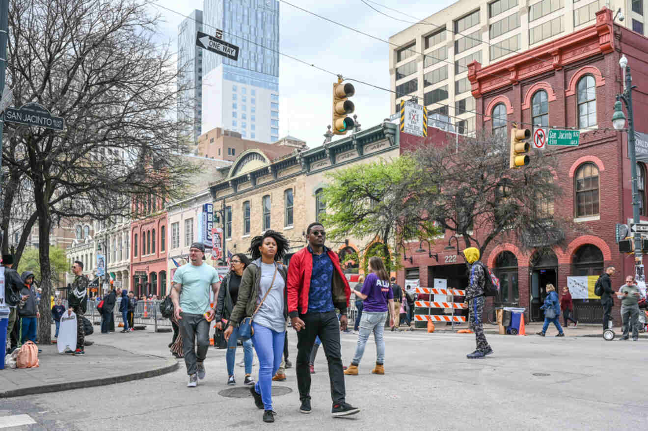 A group of people walking down a city street in the Red River Cultural District in Austin, Texas