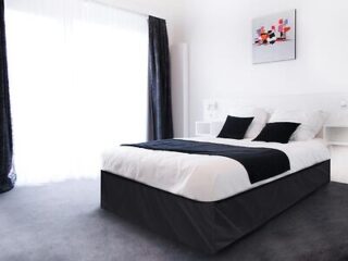 Minimalist hotel room with a large bed adorned with black and white linens and a modern art piece on the wall