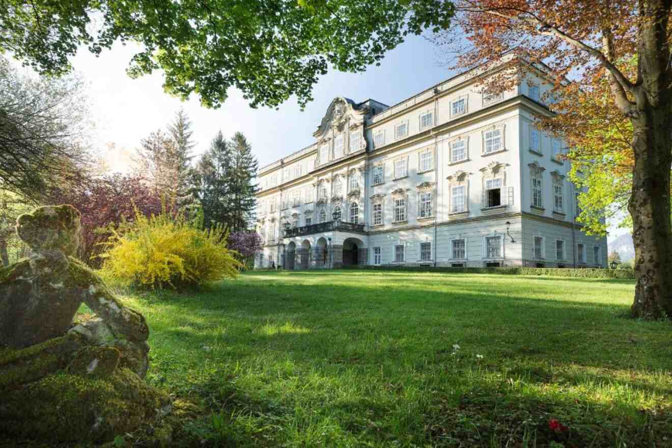 The Leopoldskron Palace in Salzburg, bathed in golden sunlight, surrounded by trees and a well-kept lawn