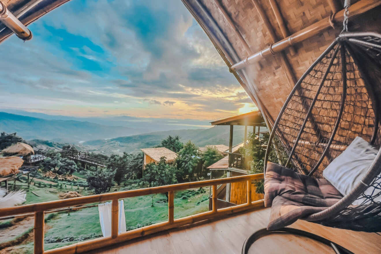 A relaxing bamboo hut balcony with a hanging egg chair, overlooking a breathtaking mountainous landscape at sunset in Chiang Mai.
