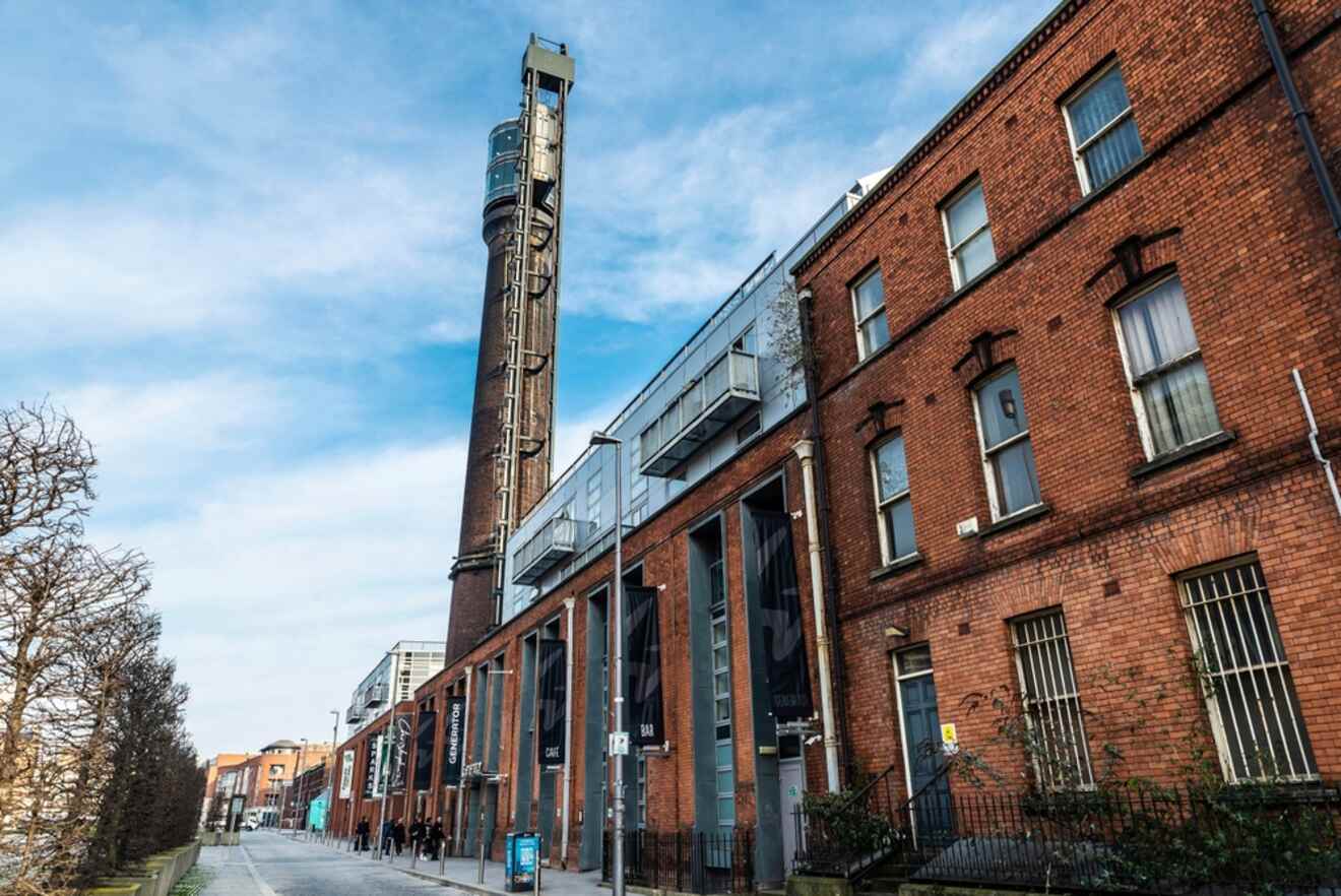 A striking view of Dublin's industrial heritage, with the tall, narrow Jameson Distillery tower juxtaposed against red-brick buildings under a blue sky