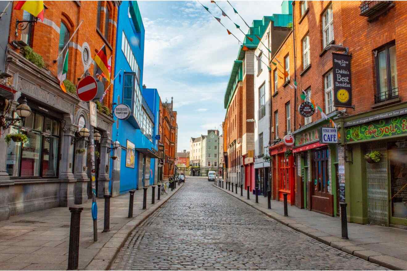 A colorful and empty urban street scene in Dublin with a mix of historical and contemporary architecture, featuring bright blue and red buildings under a clear sky
