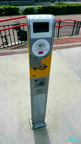 A close-up of a public transport card reader in Amsterdam, with clear instructions for contactless payment displayed on the device