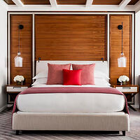 Stylish bedroom with a contemporary design, featuring a large bed with red accents, wooden sliding closet doors, and modern hanging lights.
