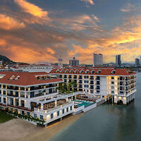 Luxurious waterfront hotel, Sofitel Legend Casco Viejo, against a dramatic sunset sky in Panama, reflecting elegance and historical charm