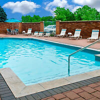 Inviting outdoor swimming pool at Courtyard by Marriott Niagara Falls with surrounding lounge chairs and a clear blue sky above