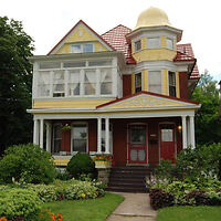 Victorian-style facade of 'A Night to Remember B&B' with a lush garden and a welcoming red entrance in Niagara Falls
