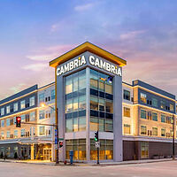 Exterior of Cambria hotel with modern design and prominent brand signage at twilight