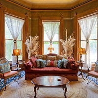 n ornate living room with a Victorian-era aesthetic, featuring plush seating, patterned drapes, and warm lighting