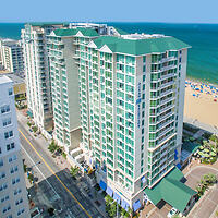 A bird's-eye view of a towering hotel building adjacent to a sandy beach