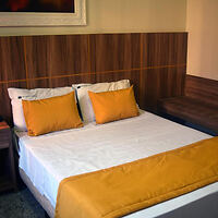 A cozy bedroom with a large bed adorned with white and orange bedding and wooden headboard