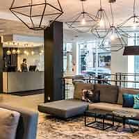 Modern hotel lobby with abstract art, stylish geometric lighting fixtures, and a neutral color scheme, offering a sleek welcome area for guests.